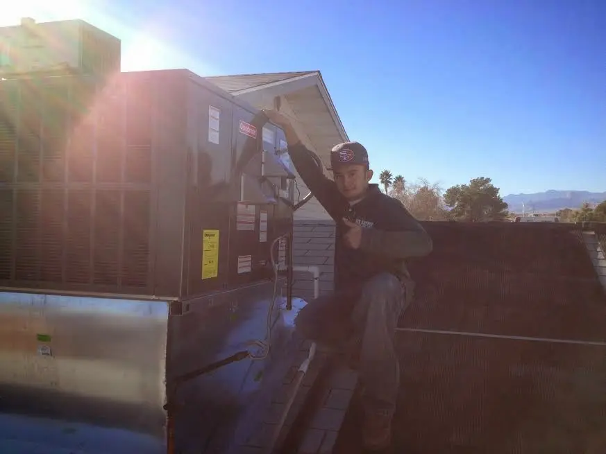 HVAC technician performing Air Duct Cleaning on a rooftop unit in Rolla